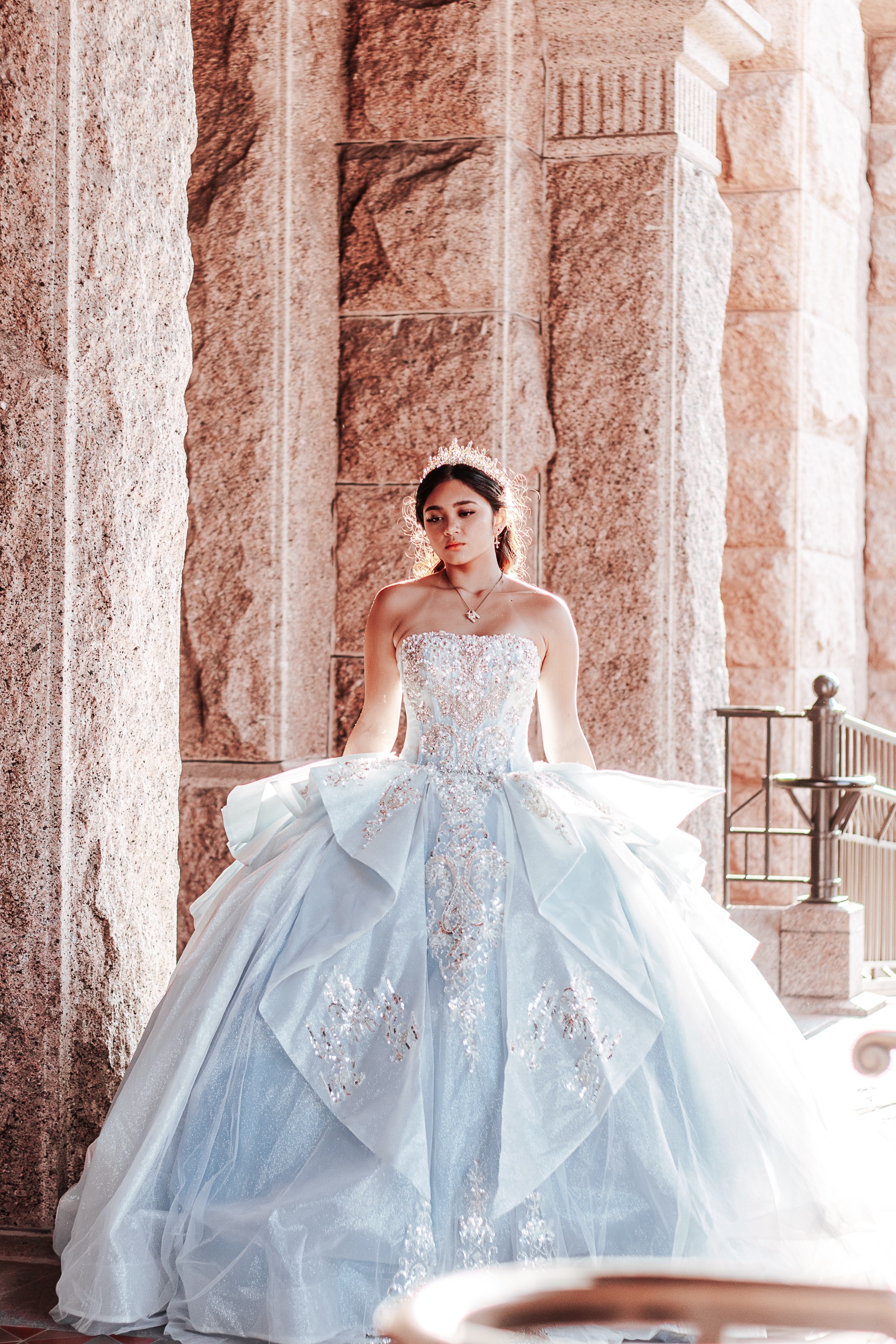 Quinceañera standing beneath the granite archways of the Texas State Capitol, photographed by Weddings by Wendi