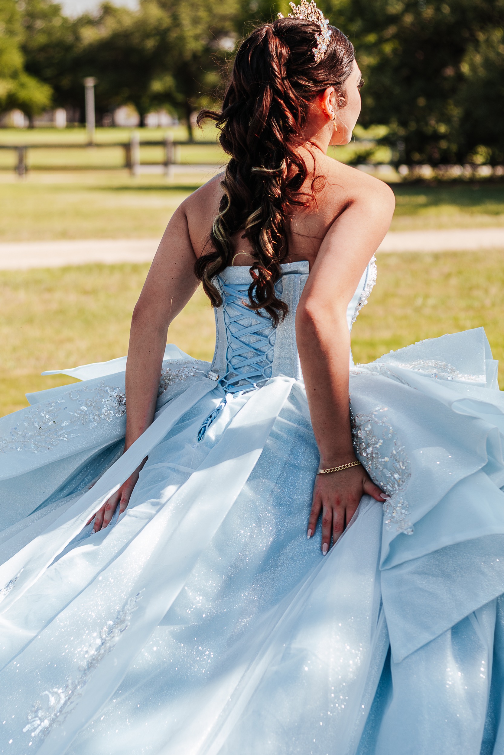 Back detail of a quinceañera's corset-laced light blue gown and tiara in an Austin park, photographed by Weddings by Wendi