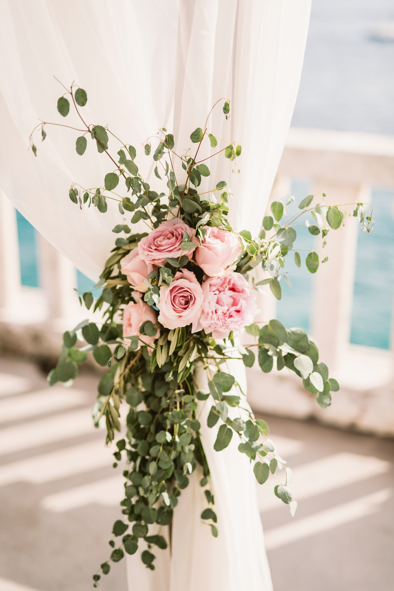 White draped wedding arch with pink floral arrangement and eucalyptus garland for Hill Country ceremony