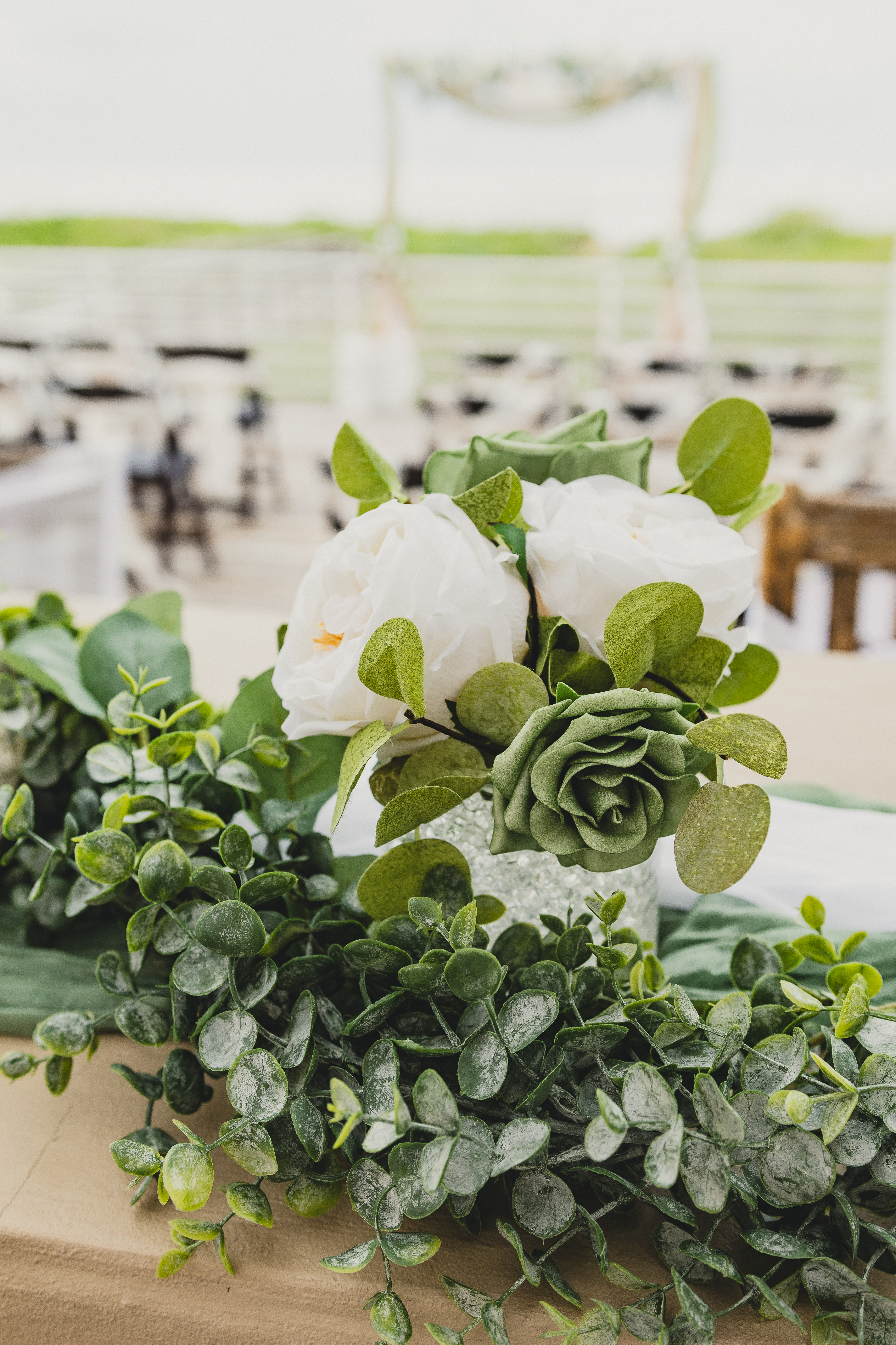 Wedding planning detail of delicate floral garland with white blooms and green succulents along table runner
