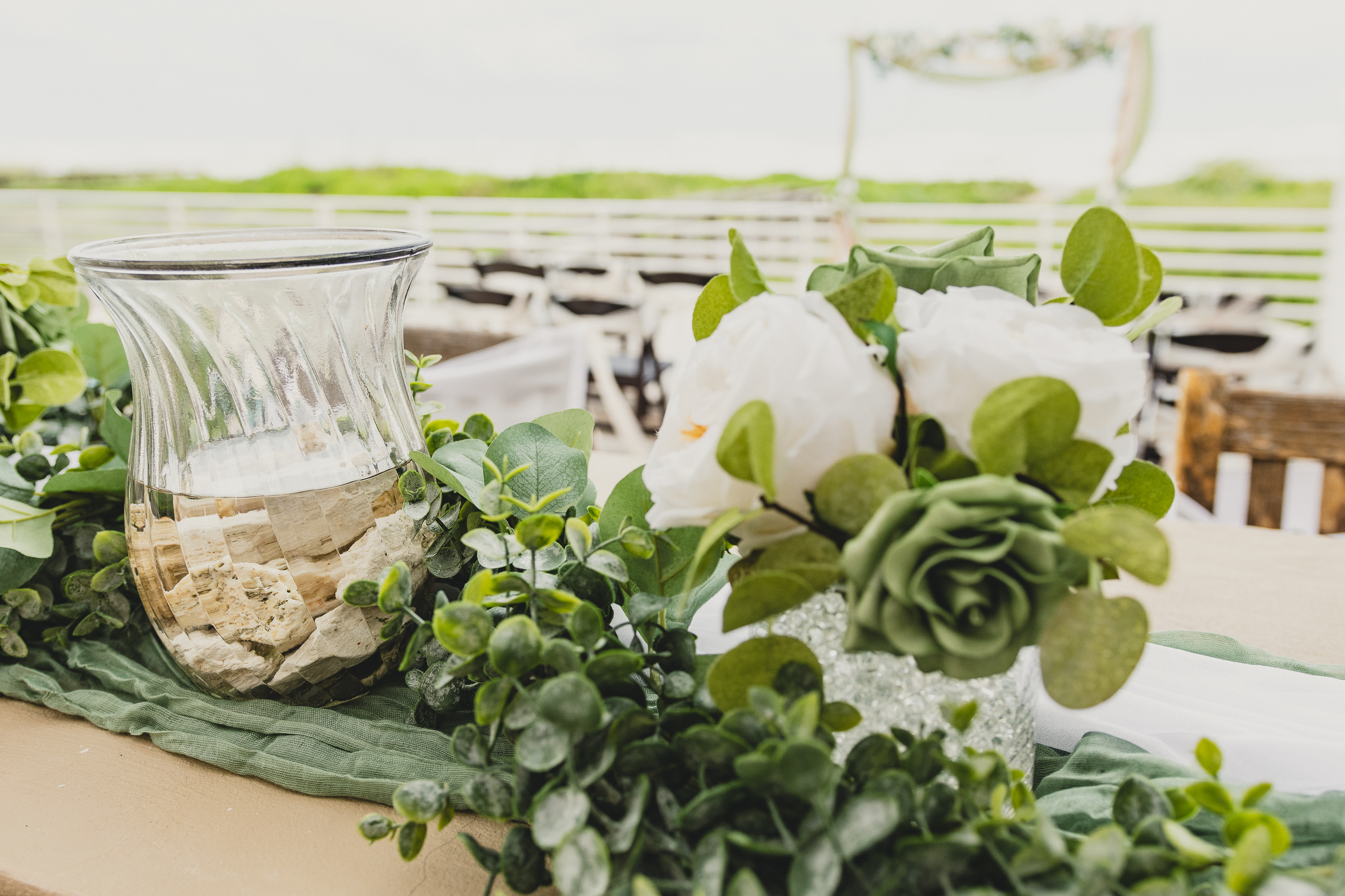 Ceremony floral arrangement combining pampas grass, dried florals, and white blooms against Hill Country backdrop