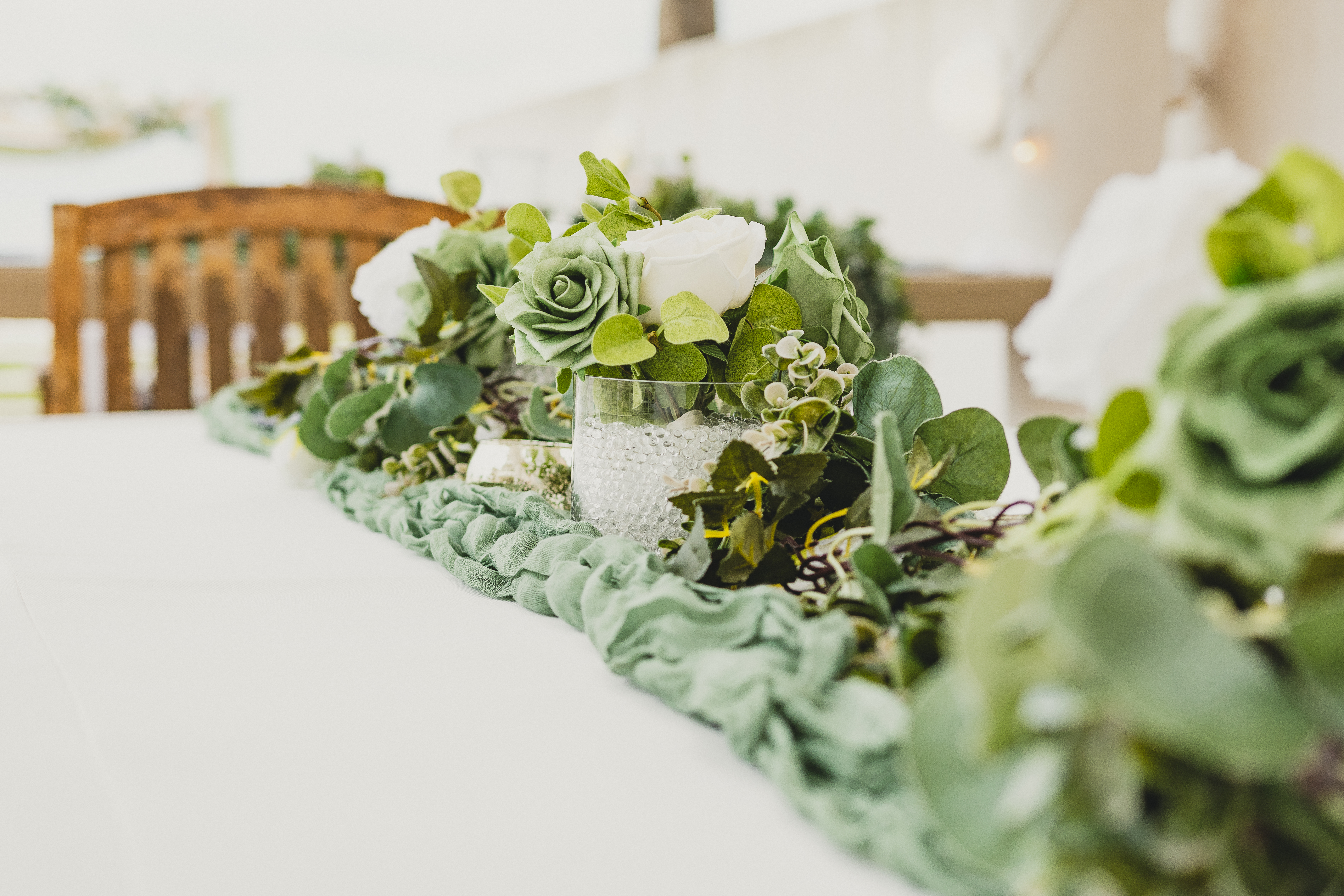 Close-up detail of pink roses and trailing eucalyptus garland on wedding ceremony arch