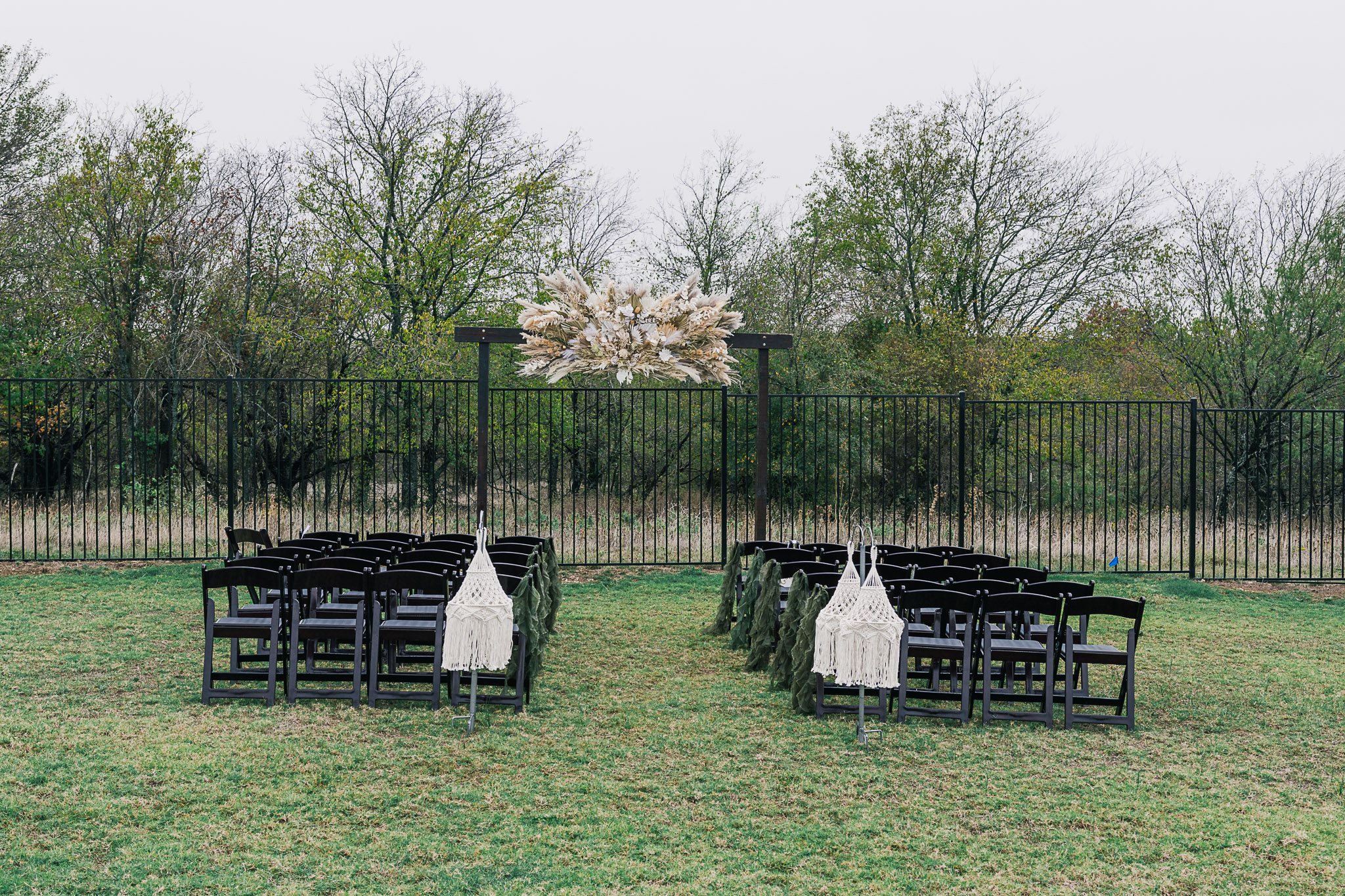 Long reception table with continuous floral and foliage runner centerpiece with draping linens and chairs