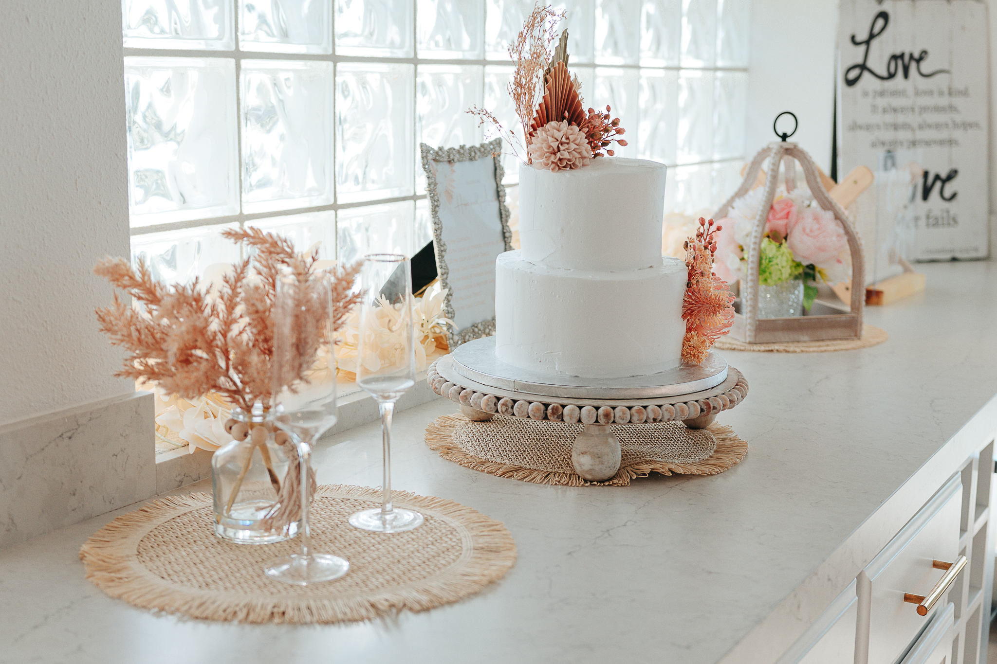 Modern reception room setup with beige linens, wooden chairs, and blush pampas grass centerpieces