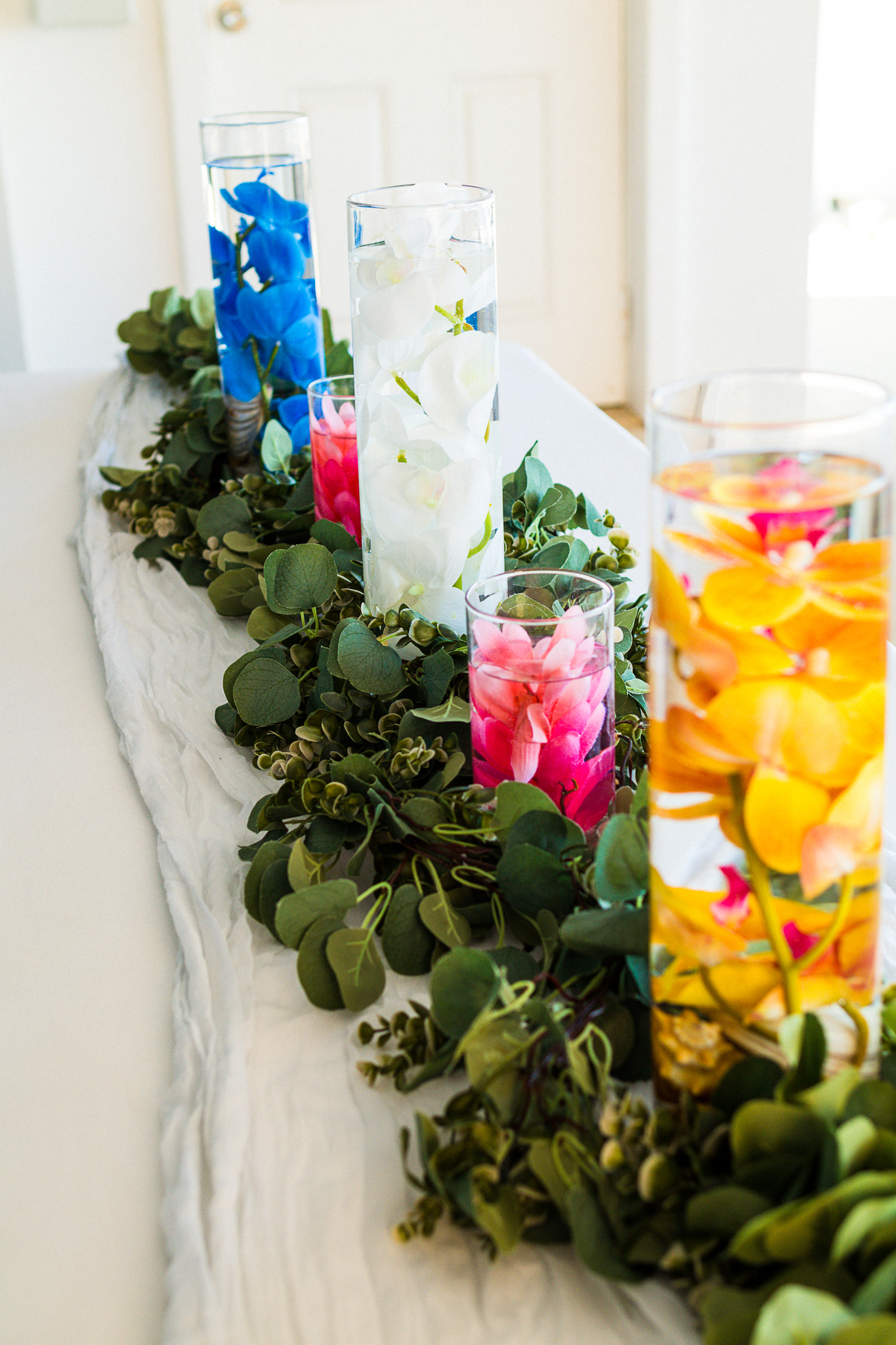 Reception table with colorful floral and foliage runner, place settings, and coordinated linens