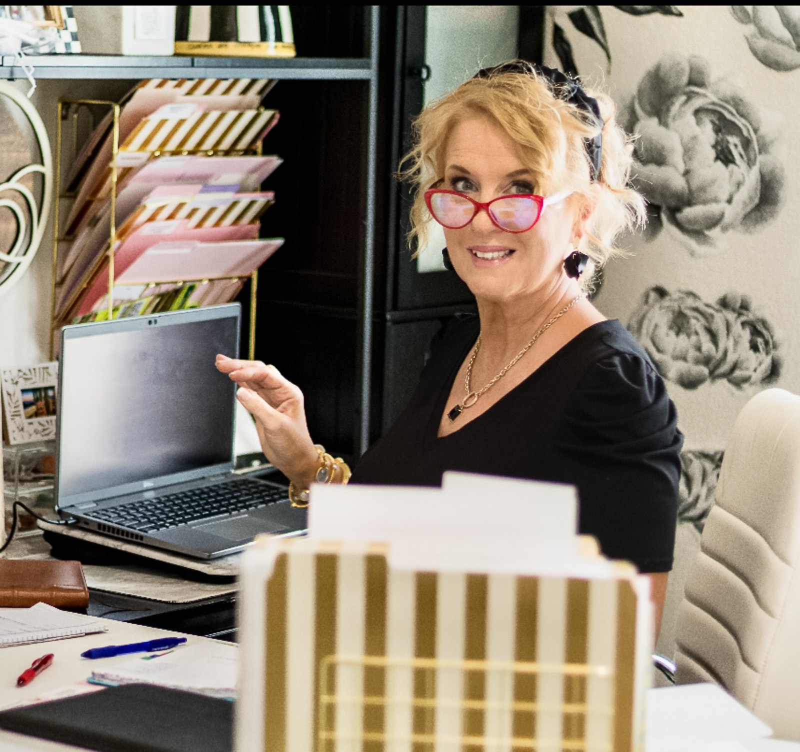 Wendi, Texas Hill Country wedding planner and founder of Weddings by Wendi, at her planning desk surrounded by binders and floral wallpaper